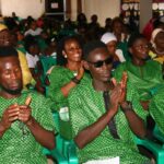 Group of people in green shirts clapping.