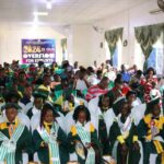 Children in graduation gowns at a ceremony.