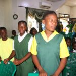 School children in green uniforms seated.